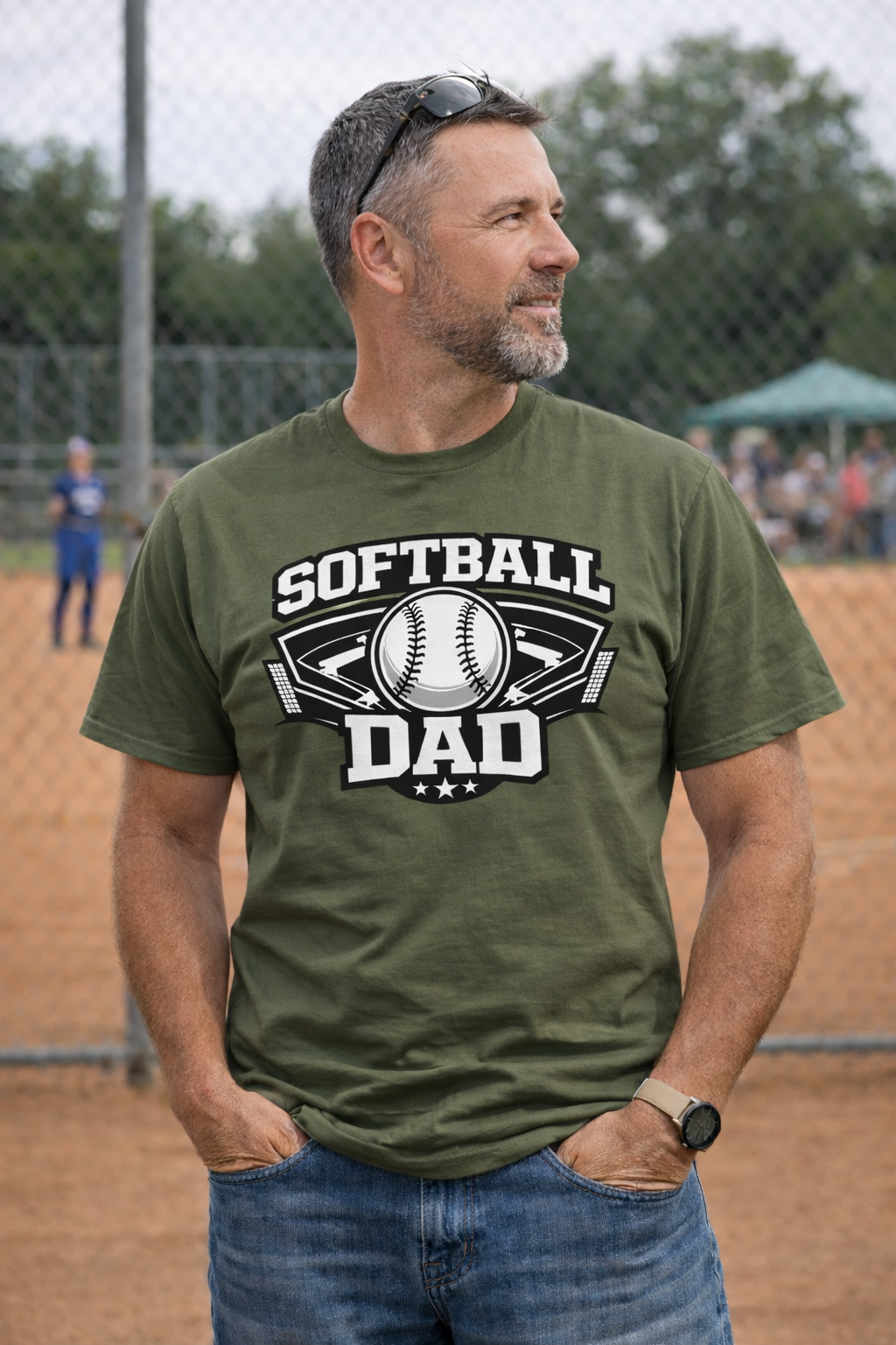 Man wearing a green 'Softball Dad' t-shirt on a sports field.